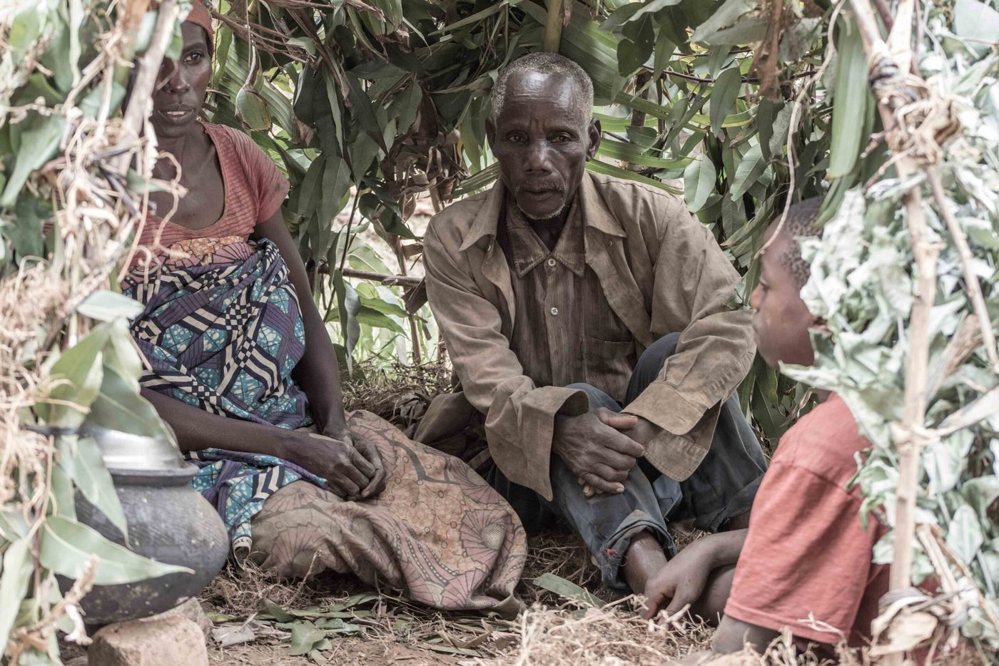 An older Burundian couple resting in their field